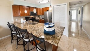 A modern kitchen with granite countertops, stainless steel appliances, and a central island with bar stools.