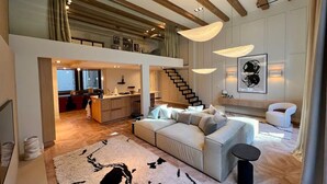 Amplia sala de estar con un sofá grande, un comedor y una escalera que sube a un nivel superior.