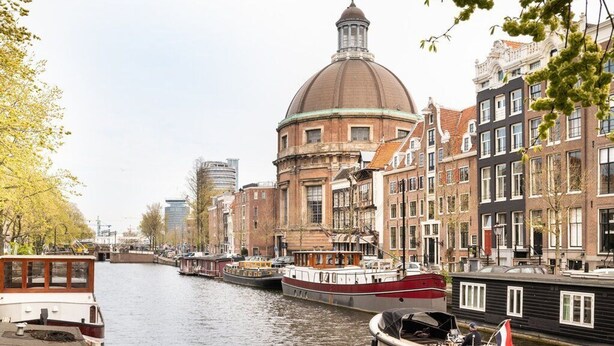 Un canal con barcos, edificios históricos y una cúpula destacada.
