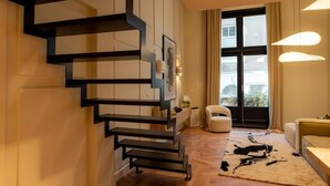 Un interior moderno con una escalera espiral, un sofá, una alfombra y una ventana con cortinas.