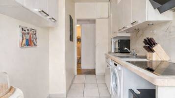 A modern kitchen with a washing machine, a microwave, and a knife block.
