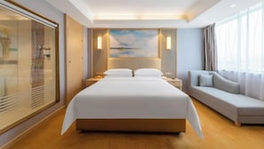 A hotel room with a large bed, a sofa, and a painting on the wall. - Vienna Hotel (Renhe subway station store of Guangzhou Baiyun International Airport) (Guangzhou)