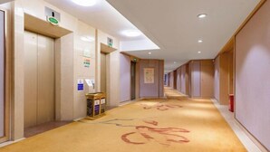 A hotel hallway with elevators, a reception desk, and a carpet with a bicycle design. - Vienna Hotel (Renhe subway station store of Guangzhou Baiyun International Airport) (Guangzhou)