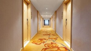 A hotel hallway with carpeted floors and wooden doors. - Vienna Hotel (Renhe subway station store of Guangzhou Baiyun International Airport) (Guangzhou)