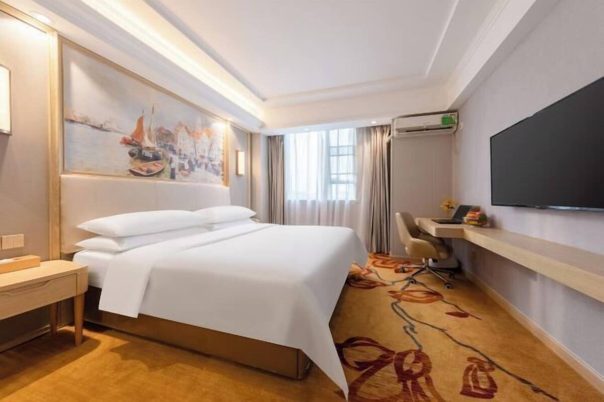 Ein Hotelzimmer mit Bett, Schreibtisch, Stuhl, Fernseher und einem Bild an der Wand.