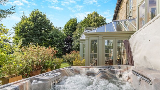 Boblebad fyldt med vand, omgivet af grønt og et solarium.