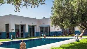 Un edificio moderno con piscina, mobiliario de exterior y césped cuidado.