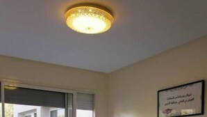Habitación de hotel con dos camas, una lámpara en el techo, un cuadro en la pared y un ventanal corredero que da a un área exterior.