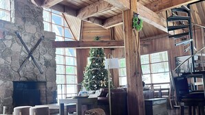 A spacious room with a stone fireplace, wooden beams, a Christmas tree, and a spiral staircase. - 3 Miles to Hidden Valley! Secluded 3BR + loft w/ WiFi, Hot Tub & Swimming Pool. (Somerset)