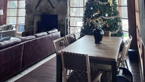 A rustic interior with a stone fireplace, wooden beams, a Christmas tree, leather seating, and a dining table. - 3 Miles to Hidden Valley! Secluded 3BR + loft w/ WiFi, Hot Tub & Swimming Pool. (Somerset)