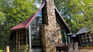 A stone cabin with a red roof, large windows, and a wooden deck with outdoor furniture. - 3 Miles to Hidden Valley! Secluded 3BR + loft w/ WiFi, Hot Tub & Swimming Pool. (Somerset)