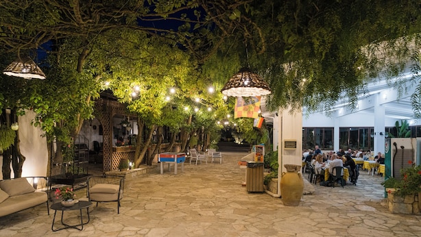 An outdoor patio area with stone flooring, seating arrangements, hanging lights, and greenery. - AGRITURISMO SCALELLE (Otranto)