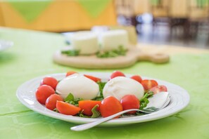 Un plato de bolitas de mozzarella y tomates cherry sobre un mantel verde.