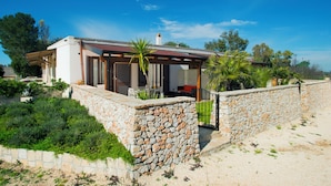 A modern house with a stone wall, a covered patio, and a view of the surrounding landscape. - AGRITURISMO SCALELLE (Otranto)