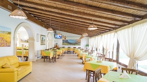 A restaurant with wooden beams, yellow tables, and a yellow sofa. - AGRITURISMO SCALELLE (Otranto)