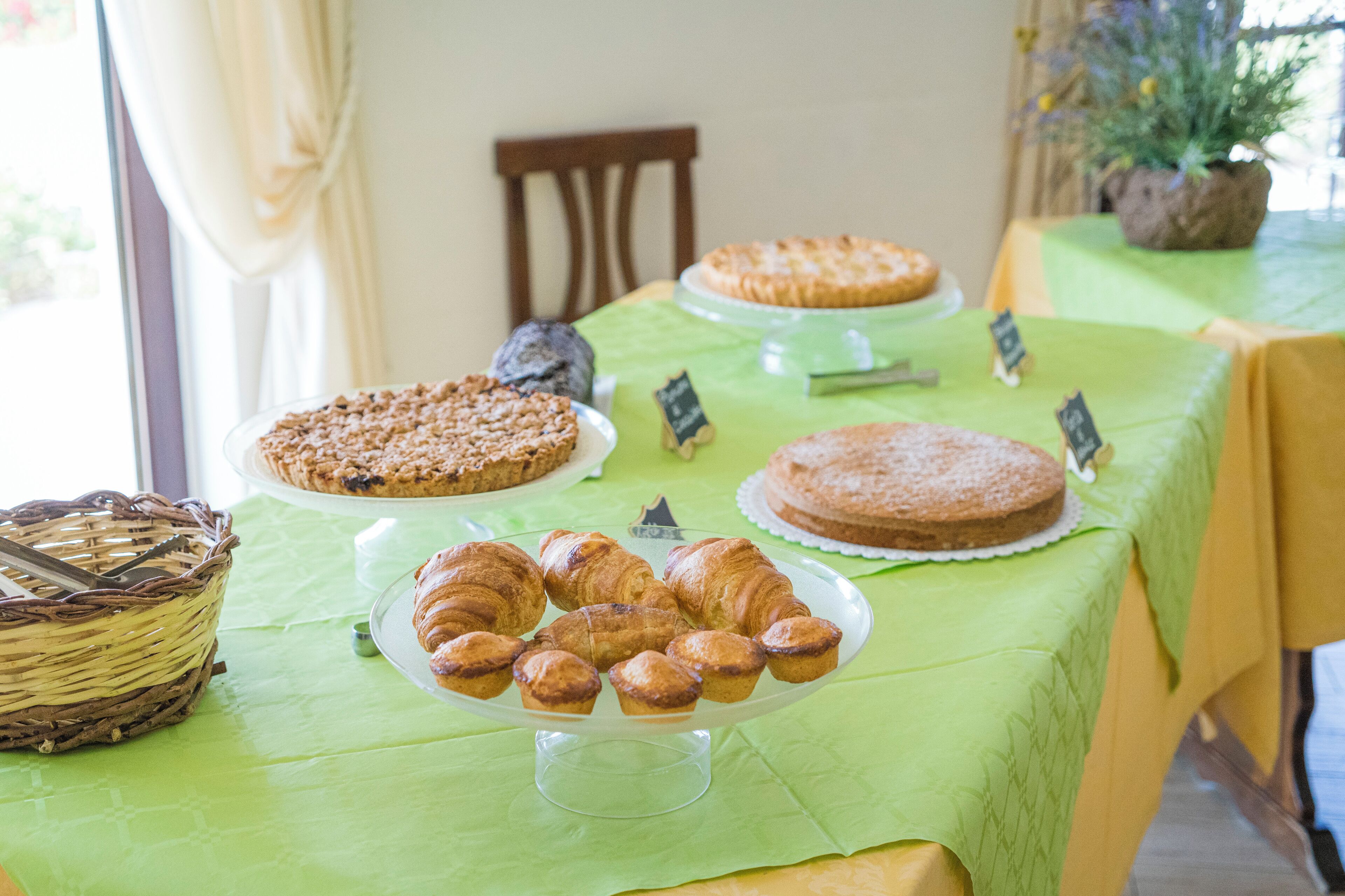 Una mesa con varias opciones de repostería, incluyendo tartas y pasteles, cubierta con un mantel verde.