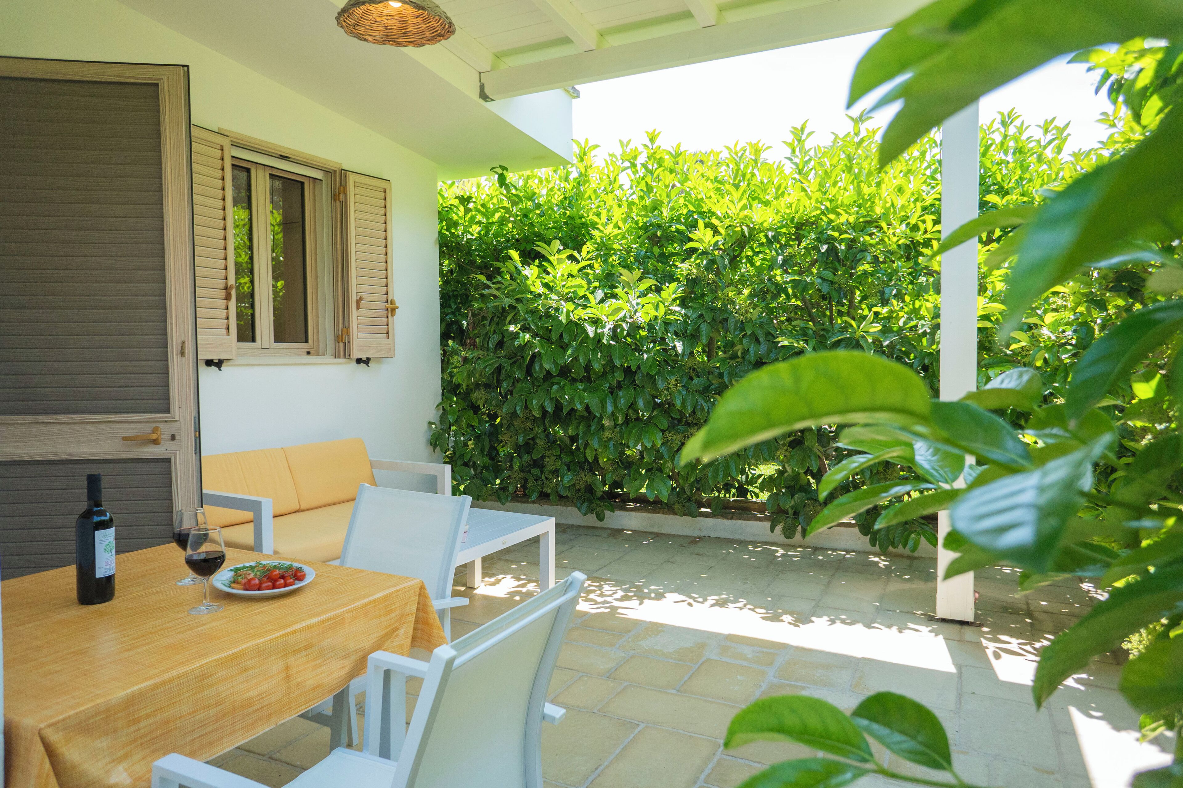 A patio with a table set for two, a bottle of wine, and a plate of food.