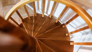 A spiral staircase with wooden steps and a curved handrail. - Corricella Hammok - Gioia Apartments (Procida)
