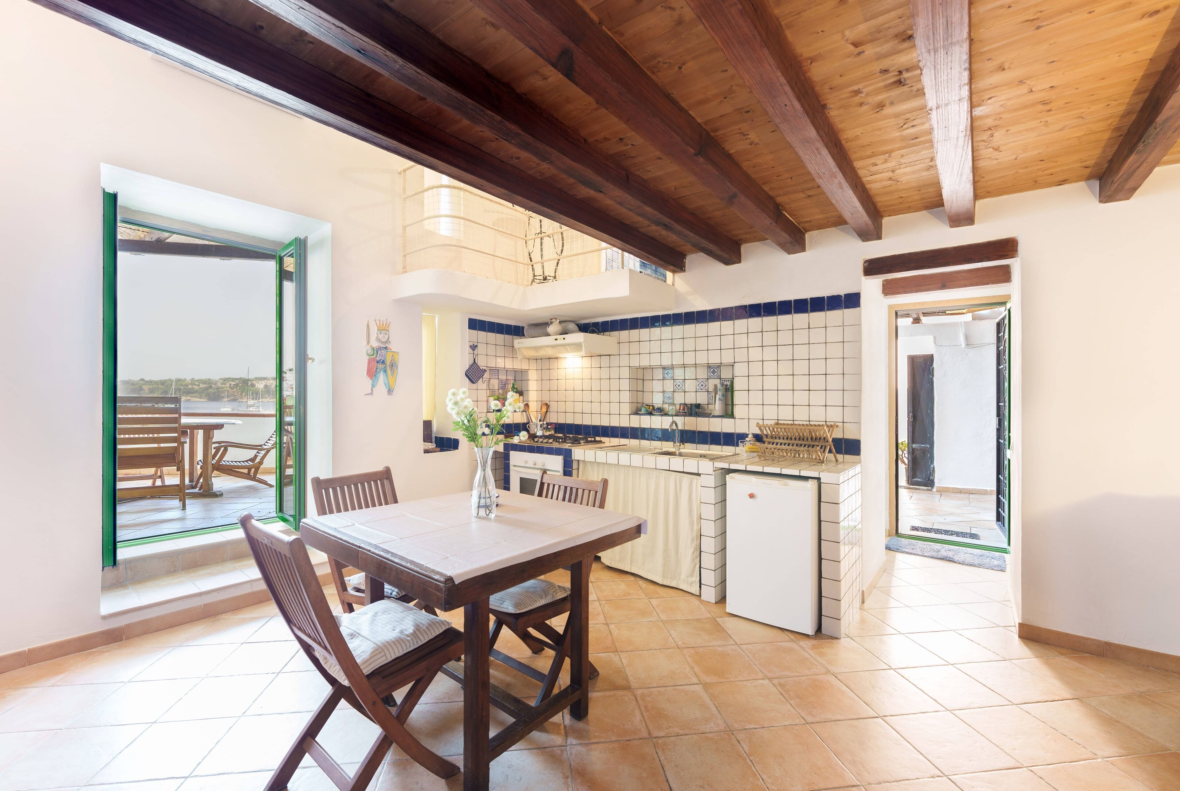 Una cocina amplia con comedor, que cuenta con techo de madera, salpicadero de azulejos y vistas a través de una puerta abierta.