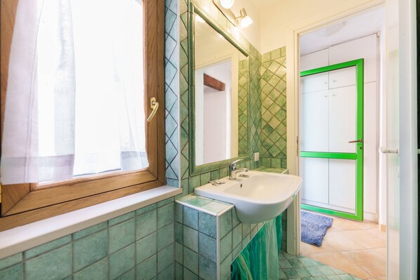 A bathroom with a sink, mirror, and green-tiled walls.