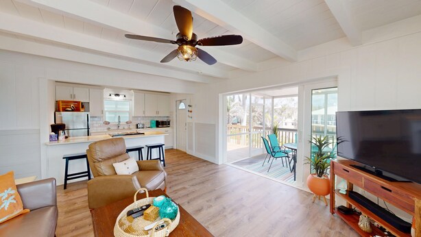 A spacious living area with a modern kitchen, a comfortable seating area, and a balcony with a TV. - Oceanview 3-bdrm home steps from beach!  Heated pool & hot tub.  Sleeps 6. (Fort Myers Beach)