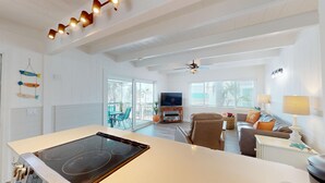 A spacious living area with a kitchen island, a dining table, and a seating area with sofas and chairs. - Oceanview 3-bdrm home steps from beach!  Heated pool & hot tub.  Sleeps 6. (Fort Myers Beach)