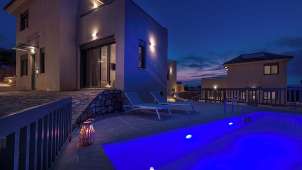 Ein modernes Haus mit Swimmingpool, Sitzgelegenheit im Freien und einer Steinmauer.