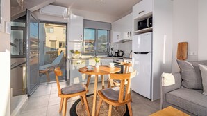 Eine moderne Küche mit weißen Geräten, ein Essbereich mit Holzkästen und ein graues Sofa.