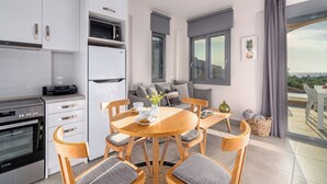 Eine moderne Küche mit weißen Schränken, einem Einbauofen und einem Essbereich mit einem runden Holztisch und Stühlen.