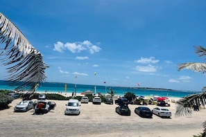 A beach with parked cars, a clear sky, and a view of the ocean.