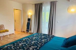 A room with a bed, a chair, a ladder, and a door.