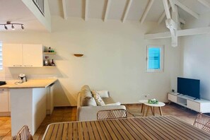 A modern kitchen with white cabinets, a coffee maker, and a dining area with a wooden table and chairs.