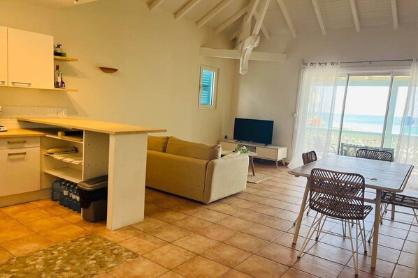 A compact living space with a kitchenette, a sofa, a TV, and a dining area with a view.