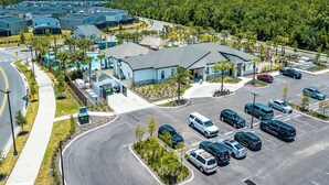 A large parking lot with multiple cars, a building with a grey roof, and a road curving around the lot. - Spacious villa with 10 bedrooms 4508 (Kissimmee)