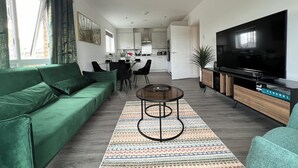 Una sala de estar moderna con un sofá verde, una mesa de centro y un televisor de pantalla plana.