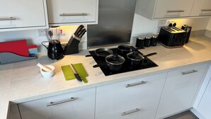 Una cocina moderna con estufa a gas, ollas, cafetera y un juego de cuchillos rojo.
