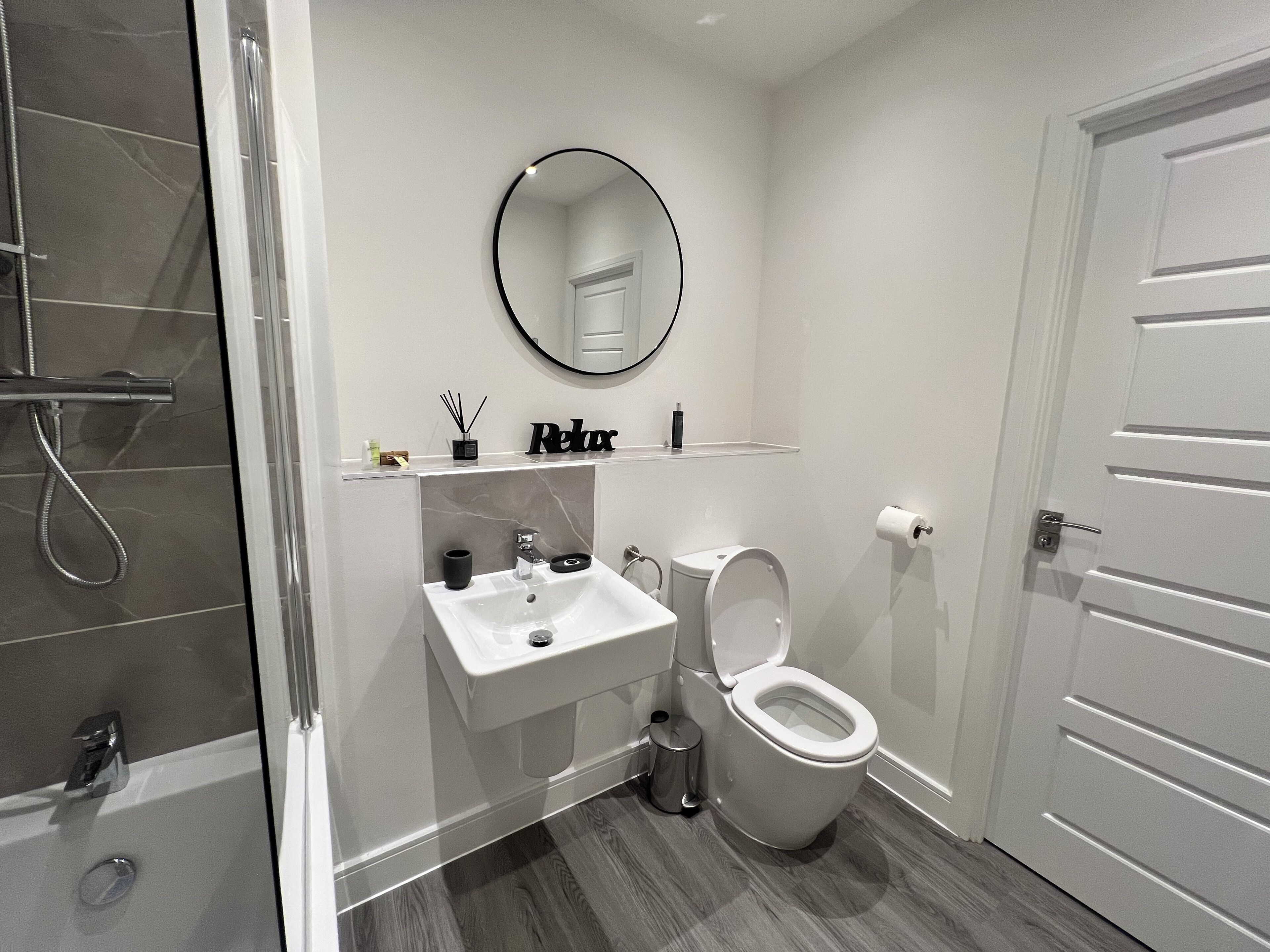 Une salle de bain moderne équipée d’une douche, d’un lavabo, de toilettes et d’un miroir au-dessus du lavabo.