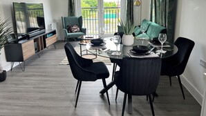 Una sala de estar moderna con comedor, un sofá, un televisor y un balcón con vistas a zonas verdes.