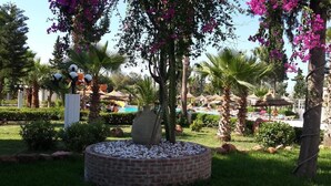 A landscaped garden with a central fountain, palm trees, and a pool area in the background. - Miramar Sharm ElKantaoui (Port El Kantaoui)