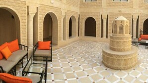 A courtyard with a patterned floor, a central decorative structure, and seating areas with orange cushions. - Miramar Sharm ElKantaoui (Port El Kantaoui)