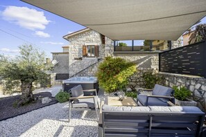 Un patio moderno al aire libre con muros de piedra, un jacuzzi y mobiliario exterior.