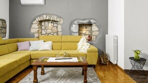 Una sala de estar con un sofá amarillo, una mesa de centro de madera y dos chimeneas de piedra.