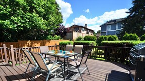 A wooden deck with a table and chairs, a grill, and a view of a house and trees. - Wonderful 4-bdrm, 2.5 bath home in Renton,15 min to Seattle,2 min to Coulon Park (Renton)