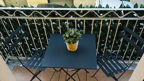 A small outdoor balcony with a table and two chairs, a potted plant, and a decorative fence. - Charming apartment with 3 bedrooms and WiFi, AC in marvelous Catania (Catania)