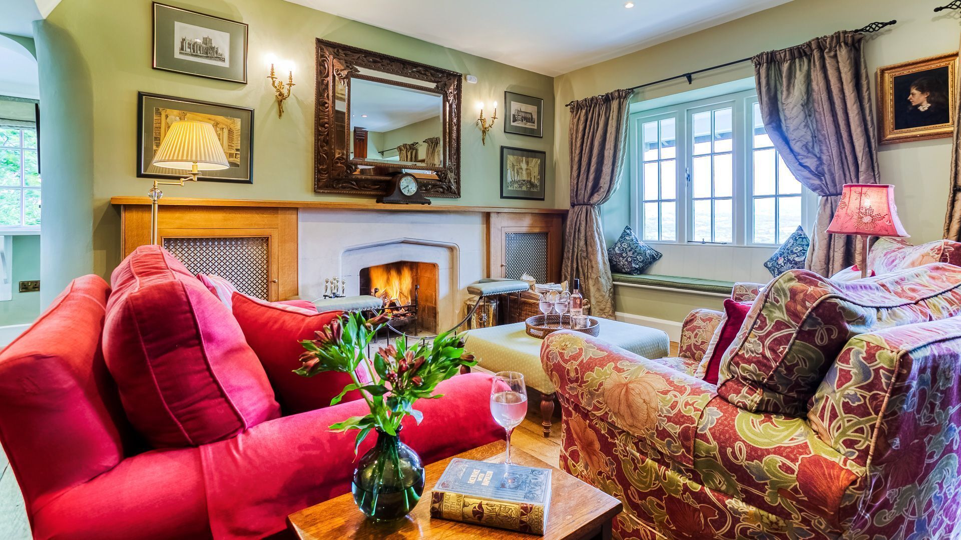 A cozy living room with a fireplace, comfortable seating, and a view of the outdoors.