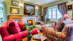 A cozy living room with a fireplace, comfortable seating, and a view of the outdoors.