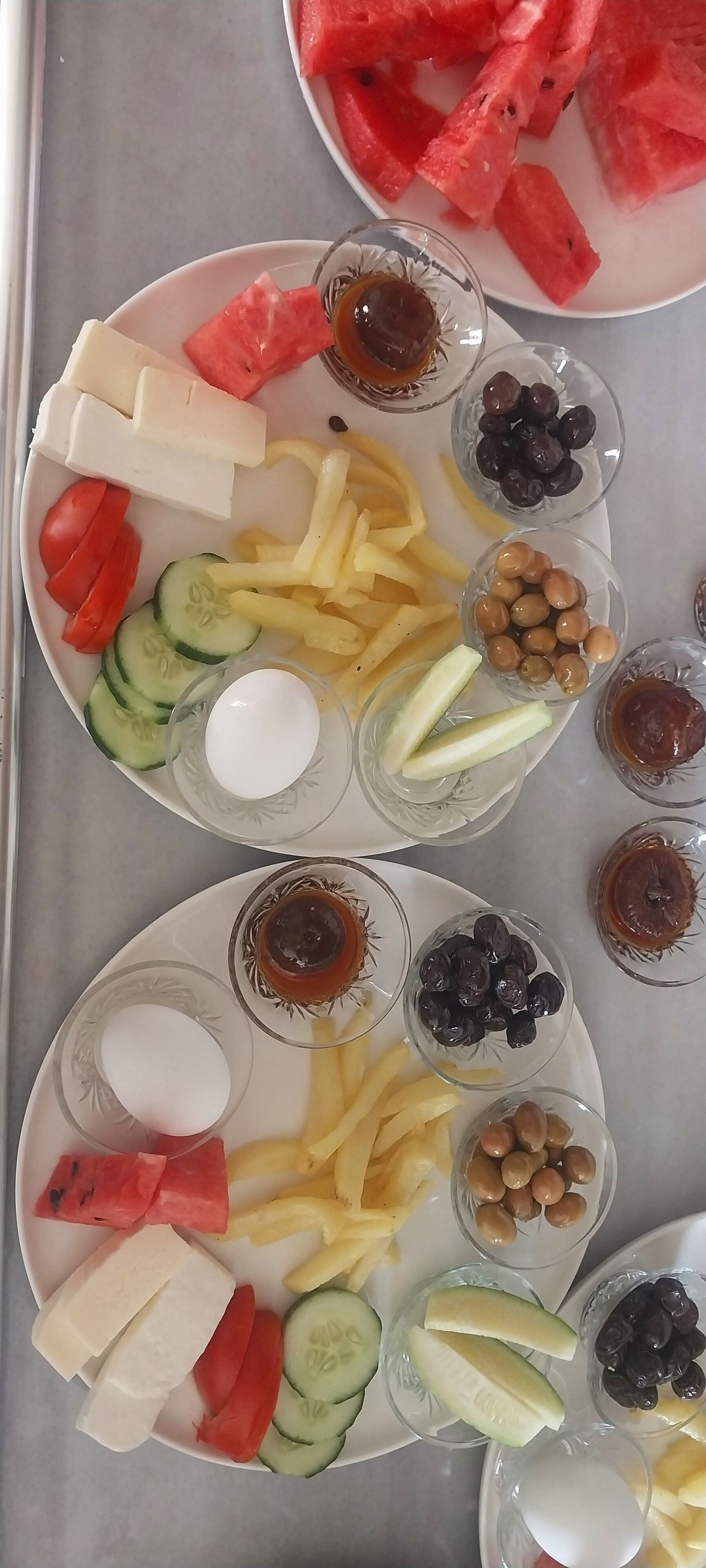 A table with various food items including watermelon, cheese, cucumbers, and olives.