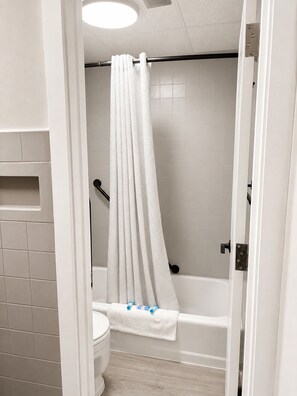 Een badkamer met een bad, toilet en een douchegordijn.