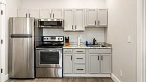 Una cocina moderna con electrodomésticos de acero inoxidable, armarios blancos y encimera de granito.