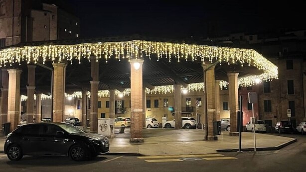 A covered parking area with columns and string lights. - The arches in the heart of Siena (Siena)